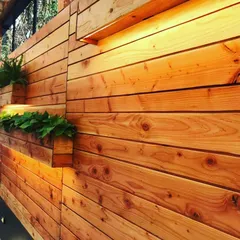 A closer view of the custom wooden planter wall in a Juhu driveway. The warm tones of the pine wood contrast beautifully with the green plants, creating a welcoming and stylish entrance.