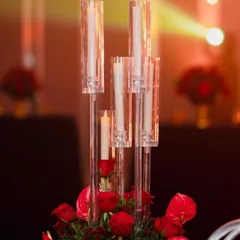 A luxurious centerpiece featuring a bouquet of deep red roses in a golden vase. This classic and elegant detail was part of a glamorous red-themed reception.