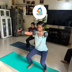 Two young girls perform goblet squats with light dumbbells, learning proper strength training form in a safe and supervised setting.