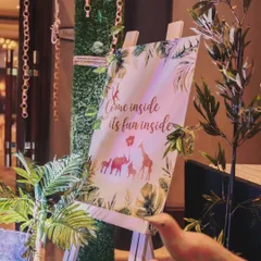 "Come inside, it's fun inside!" This charming welcome sign on an easel, surrounded by lush greenery, invited guests into Ved's jungle adventure.