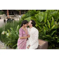 A tender forehead kiss, capturing the romance of an engagement shoot in a lush garden setting.