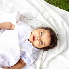 A happy baby enjoying the fresh air and soft blanket during an outdoor photoshoot. The natural light creates a beautiful, soft glow.