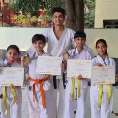 A Sensei stands with the medal winners from Purva Belmont dojo. This is a proud moment for both the students and their instructor.