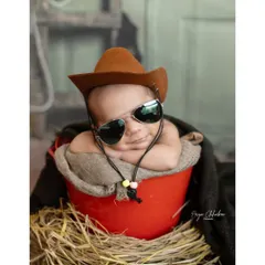 Howdy, partner! This little cowboy, complete with a hat and cool shades, is ready to wrangle some hearts. Themed shoots like this add a playful and memorable touch to your newborn's gallery.