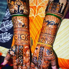 A stunning bridal design featuring the Taj Mahal, a timeless symbol of love. The arms are filled with intricate details, including couple figures, elephants, and birds, creating a rich and layered story.