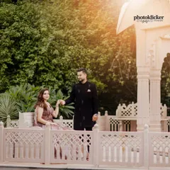 A regal shot of a couple in a formal garden setting, with the groom leading his bride, who is seated on an ornate stone bench.
