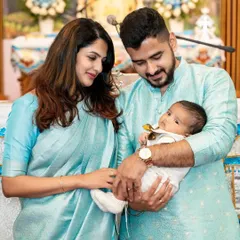 A family dressed in coordinated light blue traditional outfits during what appears to be a naming or baptismal ceremony. We capture these significant spiritual milestones with reverence.