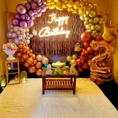 I can even turn a bedroom into a party zone for a special surprise. This setup features a vibrant rainbow-colored balloon arch over the bed, a shiny fringe curtain, and a "Happy Birthday" neon sign.