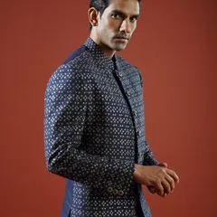 This navy blue Indo-Western jacket is adorned with a delicate, shimmering pattern, offering a contemporary take on formal wear. Its sharp tailoring and unique fabric make it a standout choice for any celebration.