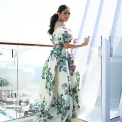 A side view of the Yara Shoemaker gown, showing the beautiful floral appliqué and the dramatic silhouette against a stunning seaside backdrop.
