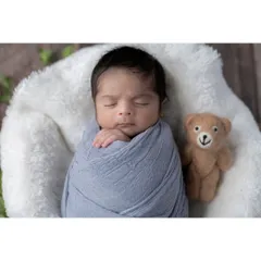 This little boy is sleeping so peacefully, swaddled in a soft blue wrap and accompanied by his teddy bear friend. I use simple, classic props that complement the baby without overwhelming the portrait.