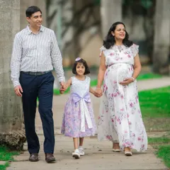 A happy family of three, soon to be four, walking hand-in-hand through a park. I love including older siblings to capture the family's growing love story.