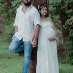 Holding hands and leaning against a tree, this pose feels natural and intimate. It's a perfect example of a casual outdoor couple maternity photo.