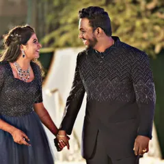 For a glamorous evening event, you can't go wrong with a coordinated black and blue theme. The groom's black Jodhpuri suit with intricate beadwork pairs beautifully with this sparkling navy blue gown.