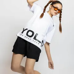 For this look, I styled a white oversized 'YOLO' graphic tee with simple black shorts and chunky sneakers. The pigtails and orange-tinted sunglasses add a playful, retro touch to the outfit.