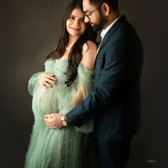A classic and intimate couple's portrait. The dad-to-be gently holds the baby bump, both sharing a quiet, happy moment.