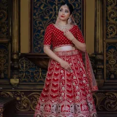 A closer look at the rich detailing on the red bridal lehenga. The velvet blouse has delicate polka dots, and the lehenga is heavily embroidered, making it a true statement piece for a bride who wants a traditional yet grand outfit.