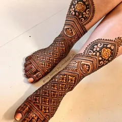 A modern take on bridal feet henna. This design uses a combination of geometric jaal patterns and shaded roses, extending up the leg for a unique and stylish look.