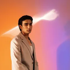 A different look from the same shoot, this time with slicked-back hair and a focus on glowing, healthy-looking skin against a colorful backdrop.
