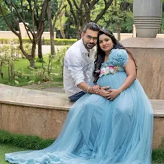 A beautiful couple portrait on a stone bench in a park, the mom-to-be radiant in a light blue gown.