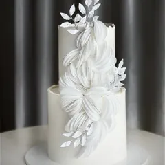 This elegant two-tiered all-white cake showcases a stunning cascade of wafer paper art. We teach you how to create these delicate, abstract floral shapes for a modern and sophisticated wedding cake design.