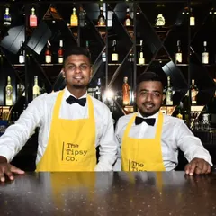 Two of our professional bartenders in their signature yellow aprons and bow ties, ready to serve. We pride ourselves on a team that is not only skilled but also personable and impeccably presented.
