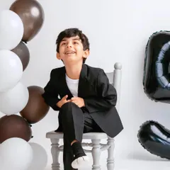 Celebrating a fifth birthday in style! This young boy looks so dapper and happy in his milestone photoshoot, complete with balloons and a smart suit.