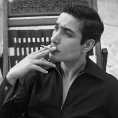 A black and white portrait that feels like a still from a classic film. The model's retro hairstyle and the act of smoking create a nostalgic and effortlessly cool vibe.