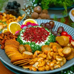 A close-up of our artisanal cheese and dip platter, featuring a dill and pink peppercorn crusted cheese ball. Surrounded by gourmet crackers, nuts, and fresh fruit, this image highlights the rich textures and fine ingredients we use.