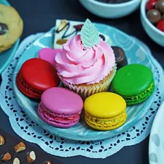 A colorful assortment of desserts including macarons, a cupcake, and chocolates on a plate. This vibrant shot is perfect for showcasing a variety of sweet treats for a bakery or dessert parlor.