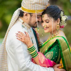 A tender moment from a Marathi wedding, capturing the couple's connection. The bride's traditional green bangles and the groom's classic white kurta create a timeless look.