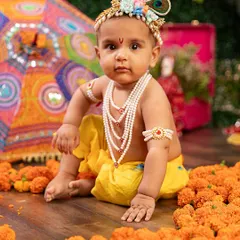 Our little Krishna sits thoughtfully amidst a sea of marigolds. The colorful Rajasthani umbrella and traditional attire make this a truly vibrant cultural portrait.