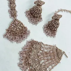 A delicate pastel pink beaded set, perfect for a Haldi or Mehendi ceremony. This rental set includes a maang tikka, hathphool, and earrings to complement your outfit.