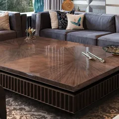 The centerpiece of this New Delhi farmhouse living room is a custom-designed coffee table with a starburst-patterned top in dyed figured veneer. Its substantial form is balanced by intricate wooden fluting and bronze detailing, creating a focal point that is both a statement and an invitation to gather.
