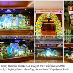 Some bunny is turning one! This adorable bunny theme for a first birthday at JCCA Club features a large backdrop with a balloon garland, a "ONE" table, and cute bunny cutouts, all set against a lush green artificial grass floor.