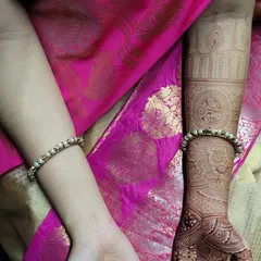 A beautiful bridal mehendi for Anushiya, set against her vibrant pink saree. The design features bold mandalas on the palm and detailed cuff work on the arms, showing how the henna complements the entire bridal look.