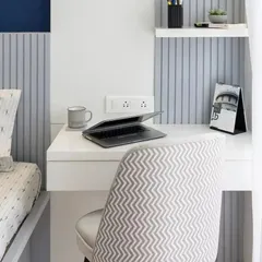 A compact and efficient workspace integrated next to the bed. The design features a simple desk, a comfortable chair, and fluted wall paneling that adds texture and visual interest.