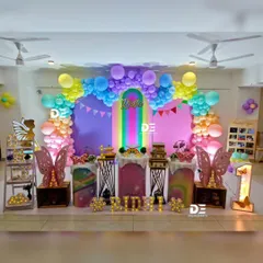This butterfly-themed first birthday is a rainbow of colors, featuring a multi-hued balloon arch, butterfly wing props, and themed cake stands for a joyful celebration.