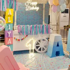 This candy-themed first birthday for Aliya was all about sweet pastels. We used a candy cart as the main backdrop, complemented by a neon 'Happy Birthday' sign, a light-up number '1', and large custom-painted name blocks.