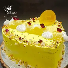 A heart-shaped Rasmalai Cake, perfect for anniversaries and special celebrations. It's adorned with meringue kisses, silver pearls, and dried rose petals for a romantic touch.