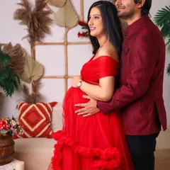 A tender moment between partners. The father-to-be gently holds her from behind, both looking forward to their new chapter in our warm, boho-themed studio.