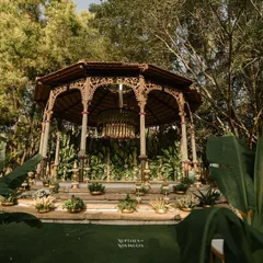 The Colonial Bandstand decorated with lush green foliage and brass lamps, showcasing a minimalist yet elegant decor theme.