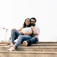 A casual, urban maternity shoot can feel so modern and real. This couple, dressed in simple jeans and white tops, shares a relaxed and confident moment together on a set of city steps.