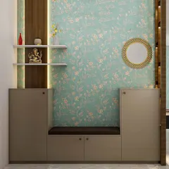 This entryway design combines a seating bench with shoe storage underneath. The floral wallpaper adds a soft, decorative touch, while the wall-mounted shelves provide a small, respectful space for a Ganesha idol, blending daily utility with a spiritual accent.