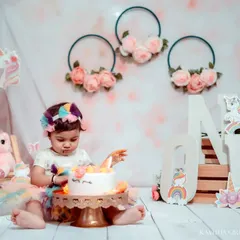 The birthday girl is ready for her cake. This shot captures her curiosity and excitement just as she's about to dig in, wearing a colorful tutu and a matching unicorn headband.
