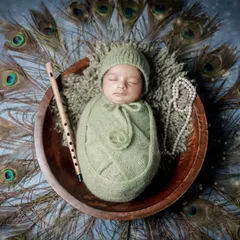 A serene Little Krishna themed portrait, one of our most requested cultural setups. This overhead shot showcases the beautiful arrangement of peacock feathers, a traditional flute, and the peacefully sleeping baby.