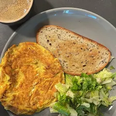 A classic breakfast plate that's both simple and nutritious. A fluffy omelette with a side of fresh greens and a slice of sourdough toast. This combination of protein, fiber, and carbohydrates is a great example of a balanced meal.
