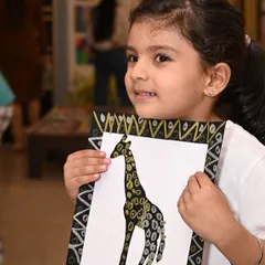 The pure joy and pride on a young artist's face when she completes her work is why I do what I do. This student is holding her beautiful giraffe painting, created during our annual exhibition project.