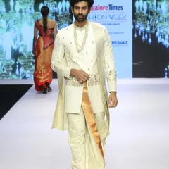 This runway look showcases a traditional South Indian outfit with a designer touch. The off-white and gold embroidered top is paired with a silk dhoti, demonstrating how heritage styles can be presented in a high-fashion context.