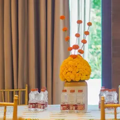A modern take on a traditional centerpiece. We used a large ceramic jar filled with a ball of yellow marigolds, with single orange marigolds rising above for a unique floral design.